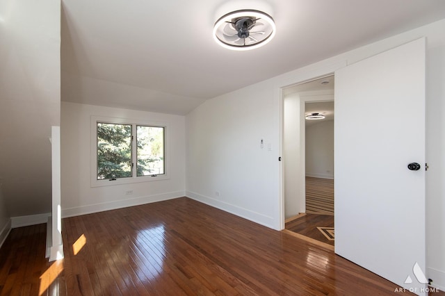 unfurnished bedroom featuring wood-type flooring, baseboards, and vaulted ceiling