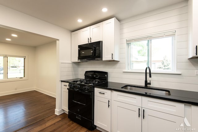 kitchen featuring black appliances, a sink, dark countertops, and recessed lighting