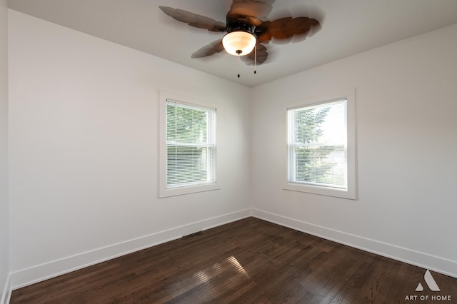 empty room featuring plenty of natural light, dark wood-style floors, and baseboards