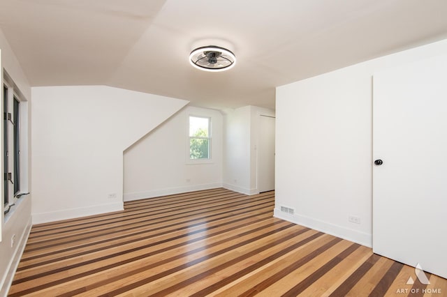 bonus room featuring vaulted ceiling, light wood-style flooring, and baseboards