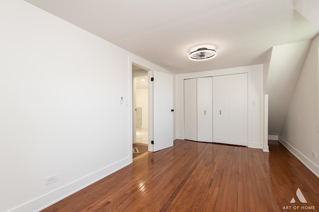 unfurnished bedroom featuring wood finished floors, baseboards, and a closet