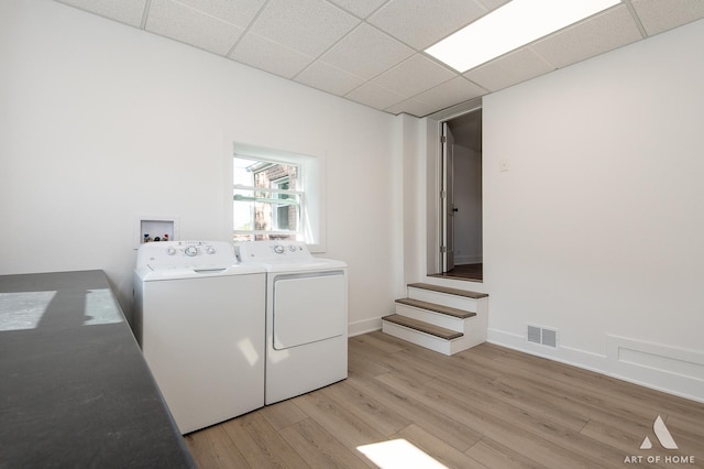 clothes washing area with washer and dryer and light wood finished floors