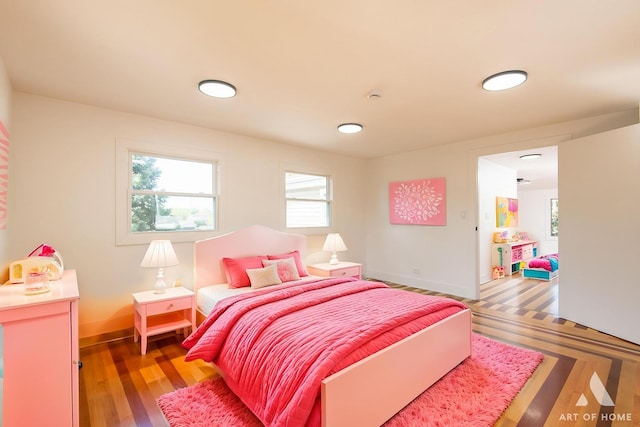 bedroom featuring multiple windows, baseboards, and light wood finished floors