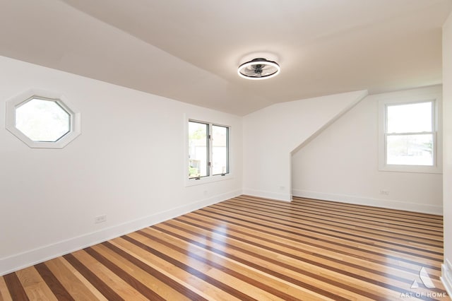 additional living space with lofted ceiling, baseboards, and light wood-type flooring