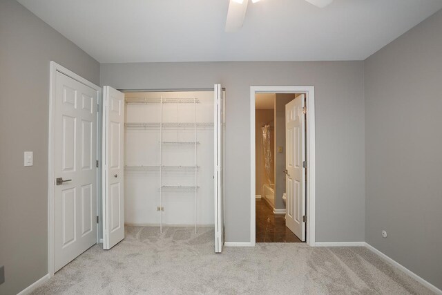 unfurnished bedroom featuring carpet flooring, baseboards, a closet, ensuite bathroom, and a ceiling fan