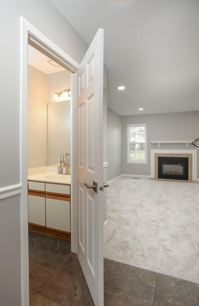 bathroom with vanity, a fireplace, recessed lighting, and baseboards