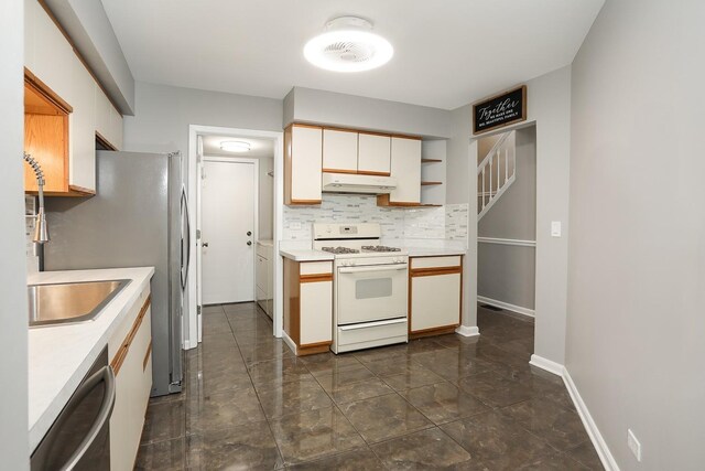 kitchen featuring white gas stove, under cabinet range hood, light countertops, and decorative backsplash