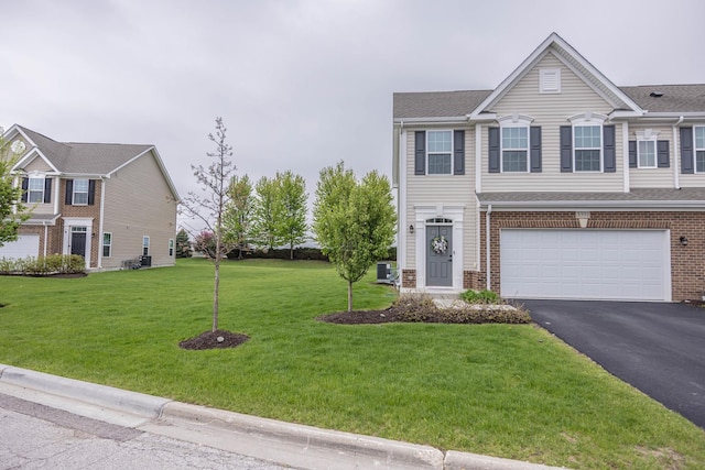 view of front of house featuring asphalt driveway, brick siding, a front yard, and a garage