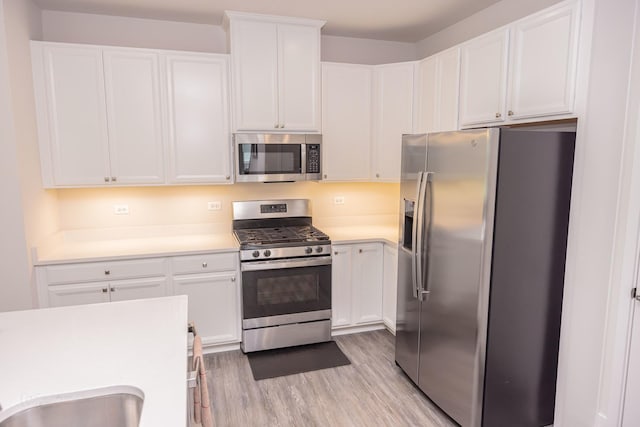 kitchen featuring appliances with stainless steel finishes, light wood-style floors, light countertops, and white cabinets