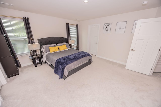 bedroom with light colored carpet and baseboards