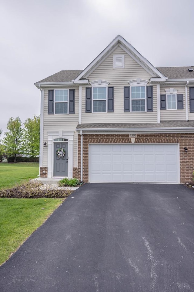multi unit property with brick siding, driveway, and an attached garage