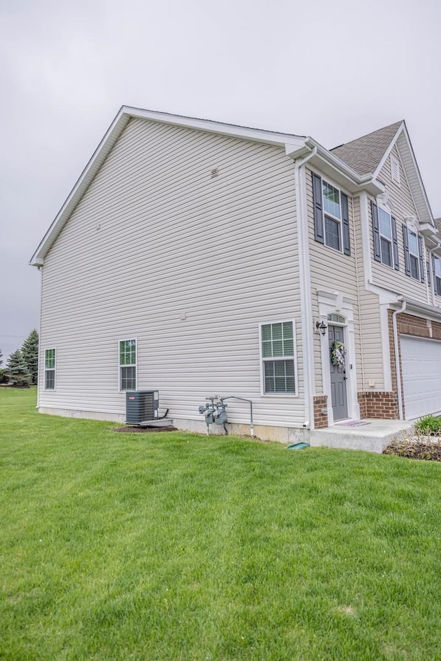 view of property exterior with central air condition unit, a lawn, and an attached garage