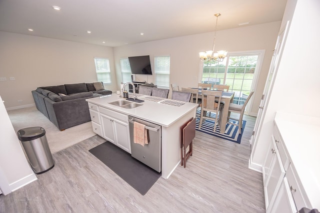 kitchen with a sink, dishwasher, light wood finished floors, a chandelier, and white cabinets