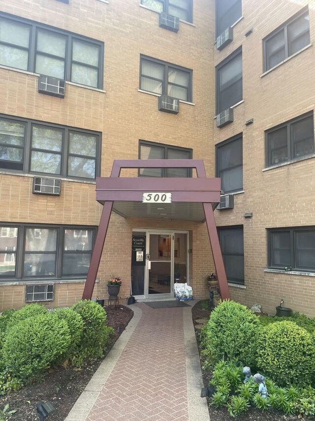 property entrance featuring brick siding and a wall mounted AC