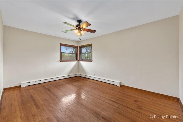 spare room featuring ceiling fan, hardwood / wood-style flooring, a baseboard radiator, and baseboards