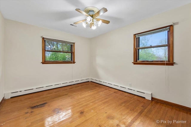 empty room with healthy amount of natural light, wood-type flooring, baseboards, and ceiling fan