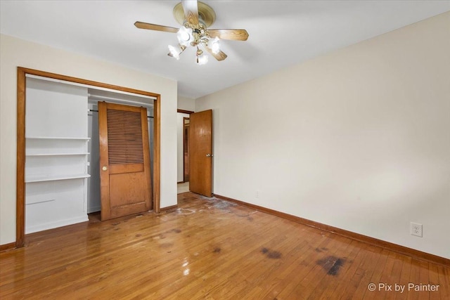 unfurnished bedroom with baseboards, wood-type flooring, a closet, and a ceiling fan