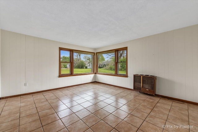 tiled spare room featuring baseboards and a textured ceiling