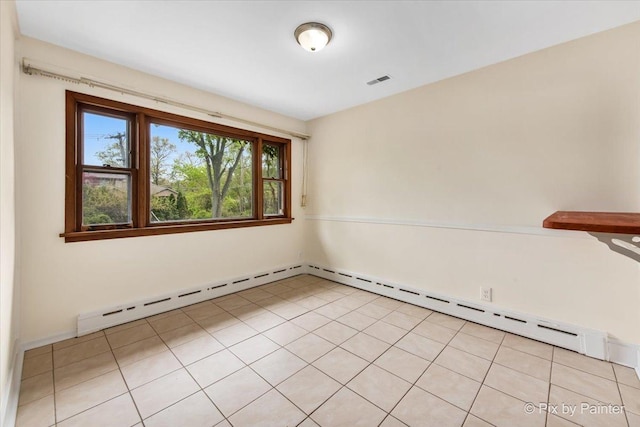 spare room featuring baseboard heating and light tile patterned floors