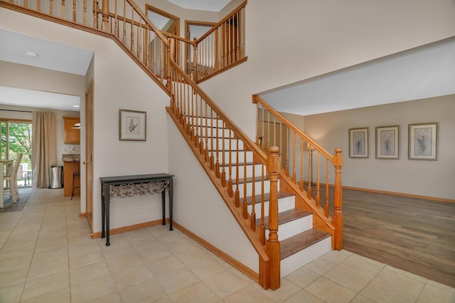 stairway featuring baseboards and a high ceiling