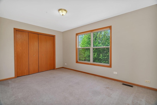 unfurnished bedroom with baseboards, carpet floors, and a closet