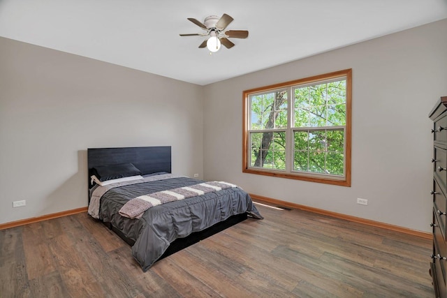 bedroom with baseboards, wood finished floors, and a ceiling fan