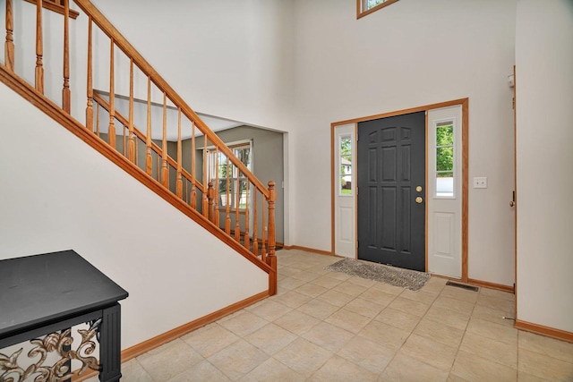 entryway with baseboards, stairs, and a towering ceiling