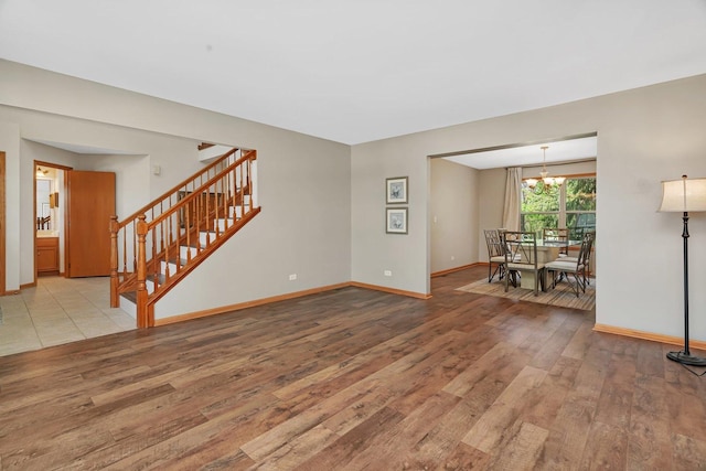 living room featuring hardwood / wood-style floors, stairs, baseboards, and a chandelier