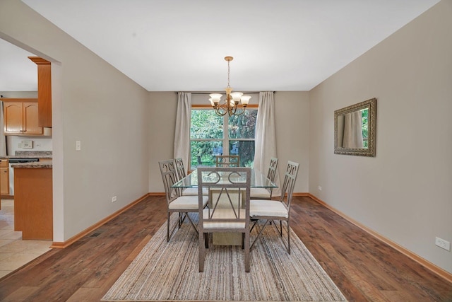 dining room featuring wood finished floors, a chandelier, and baseboards