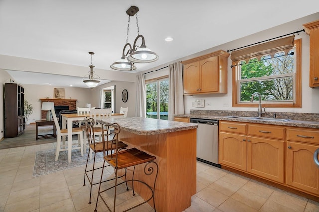 kitchen featuring dishwasher, a sink, a center island, a breakfast bar area, and decorative light fixtures