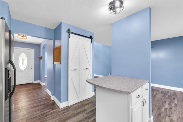 19 Nightingale Cir, Camargo, IL 61919 - kitchen featuring dark wood finished floors, fridge with ice dispenser, a barn door, arched walkways, and white cabinetry