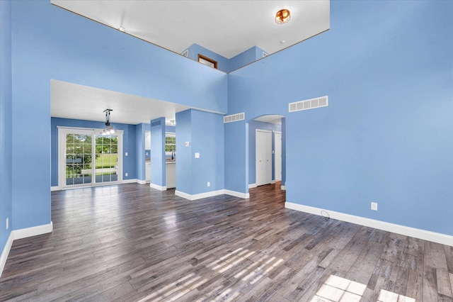19 Nightingale Cir, Camargo, IL 61919 - unfurnished living room with arched walkways, wood finished floors, baseboards, and a towering ceiling