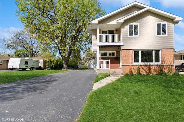 view of front facade featuring brick siding, a balcony, and a front lawn