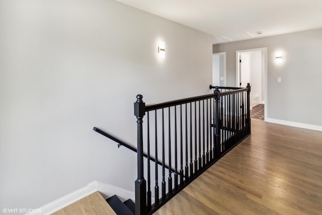 staircase featuring wood finished floors and baseboards