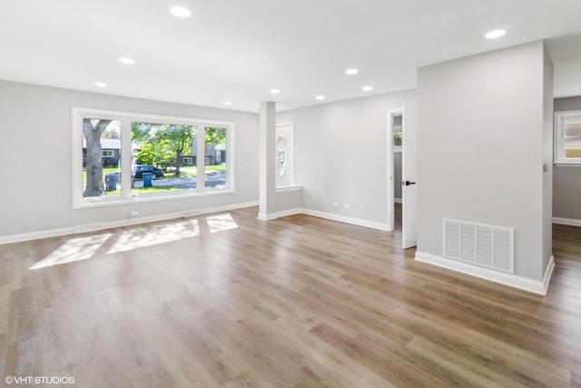 unfurnished living room featuring plenty of natural light, recessed lighting, wood finished floors, and baseboards