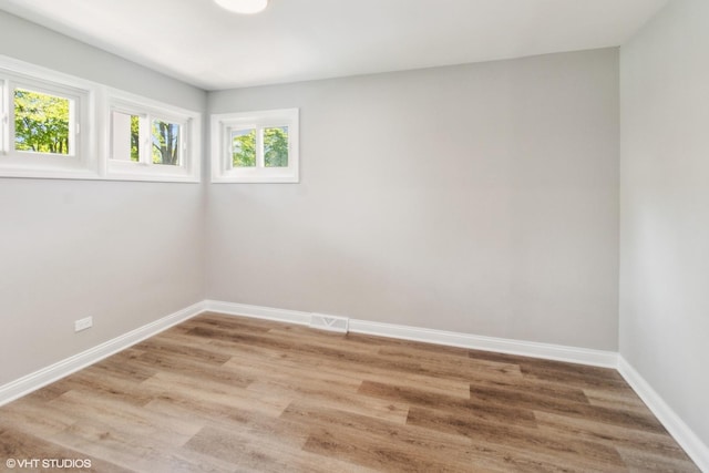 spare room with baseboards and light wood finished floors