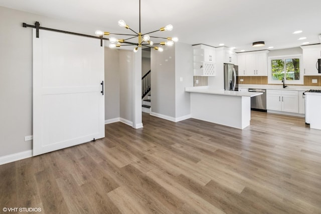 kitchen featuring stainless steel appliances, a sink, a chandelier, baseboards, and white cabinets