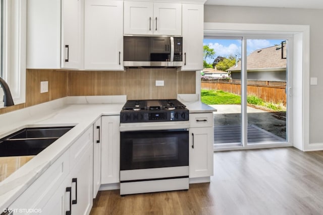 kitchen with gas range, stainless steel microwave, and white cabinetry