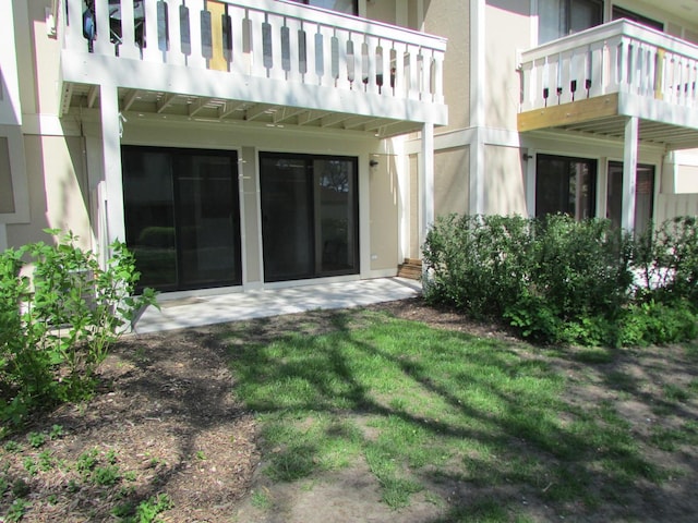 rear view of house with stucco siding and a balcony