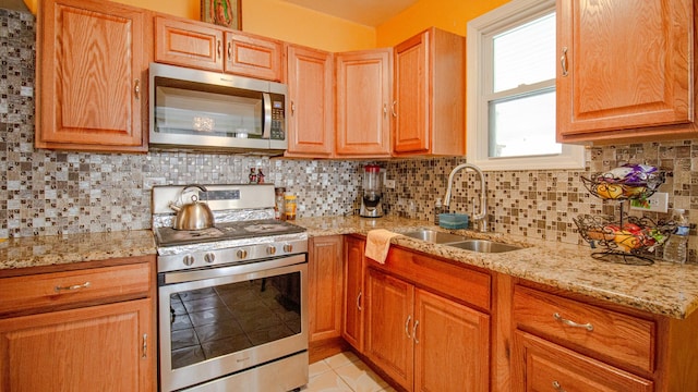 417 52nd Ave, Bellwood, IL 60104 - kitchen featuring stainless steel appliances, a sink, light stone countertops, light tile patterned floors, and backsplash