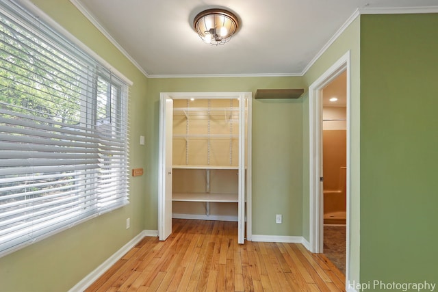 interior space featuring multiple windows, a closet, light wood finished floors, and crown molding