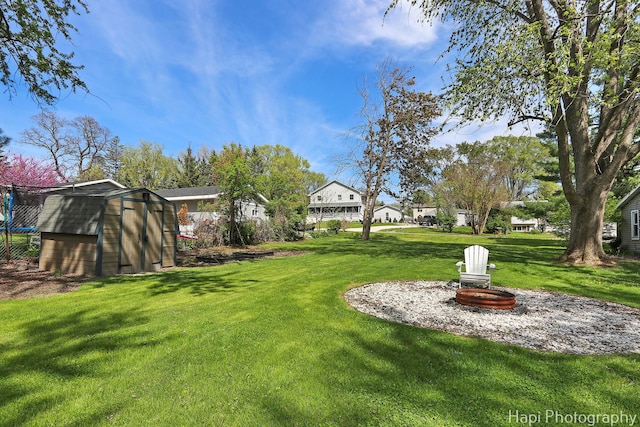 view of grassy yard with a shed, an outdoor structure, and a trampoline
