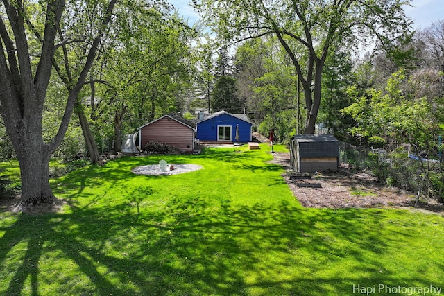 view of green lawn with an outdoor structure, a shed, and view of scattered trees