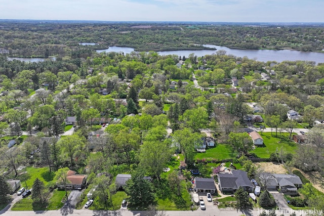 aerial view of residential area with a large body of water and a heavily wooded area