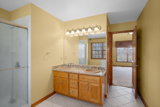 bathroom with tile patterned flooring, a stall shower, double vanity, and baseboards