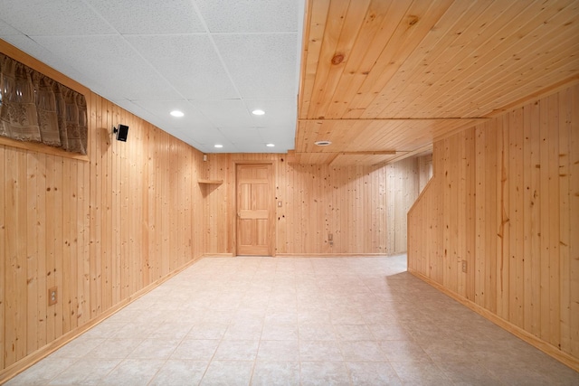 finished below grade area featuring wood walls, recessed lighting, tile patterned floors, and baseboards