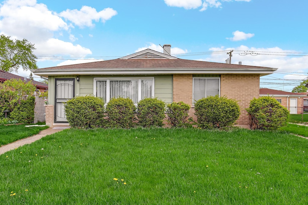1383 Greenbay Ave, Calumet City, IL 60409 - view of front of home with brick siding, a front lawn, and a chimney
