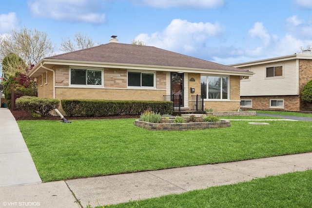 view of front facade featuring brick siding, a front yard, a chimney, and roof with shingles