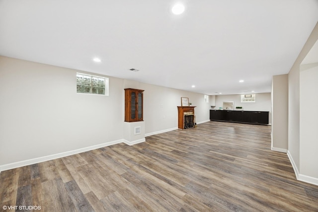 unfurnished living room featuring wood finished floors, recessed lighting, baseboards, and bar area