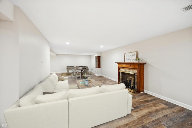 living room with wood finished floors, baseboards, recessed lighting, and a fireplace with flush hearth